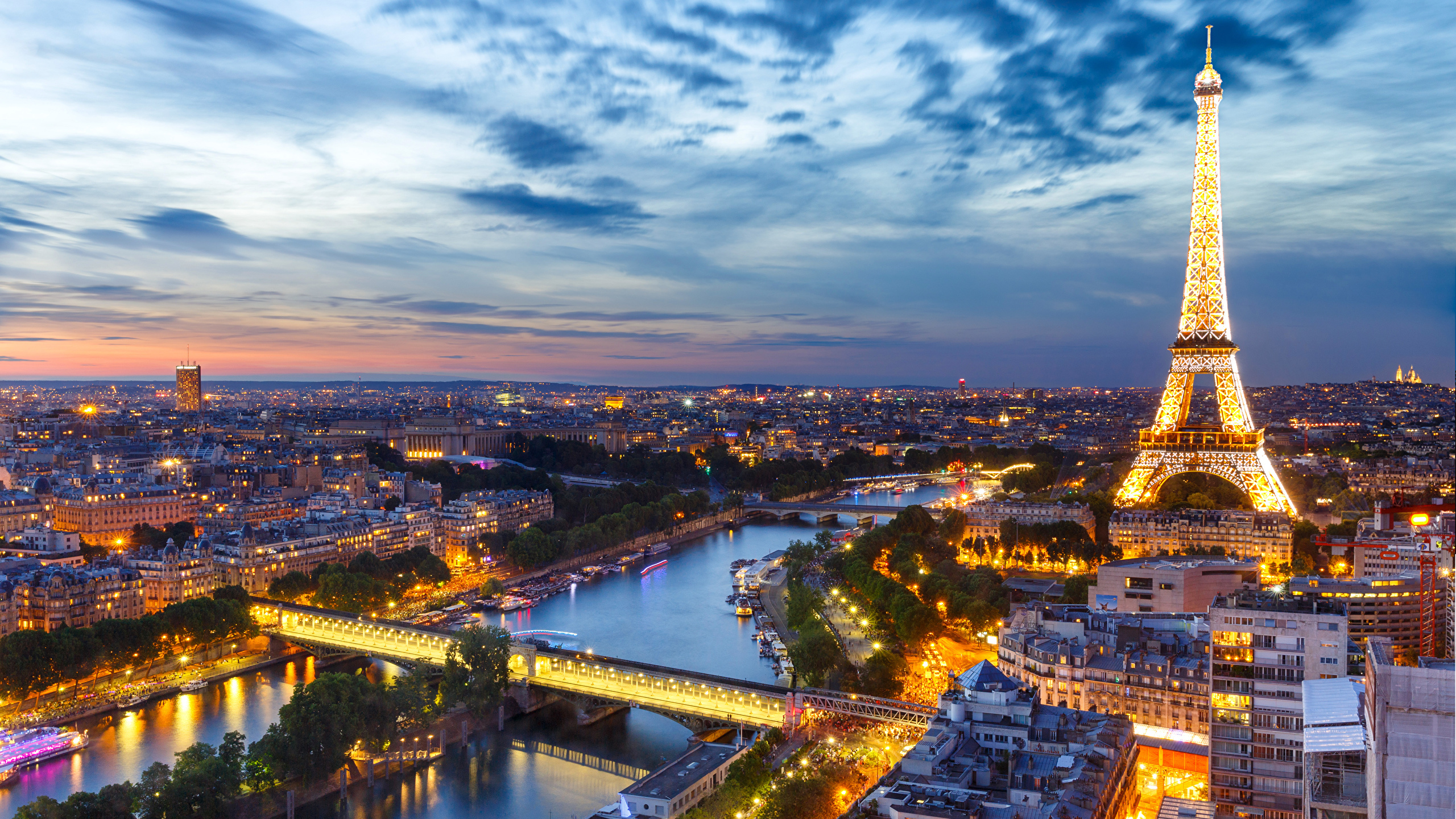 Stunning evening view of Paris featuring the illuminated Eiffel Tower from above with dramatic sky