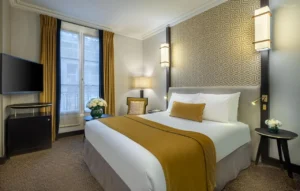 Le Marquis Eiffel -hotellin moderni kahden hengen huone, sisustettu kullan ja beigen sävyillä.