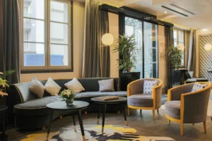 Le Marquis Eiffel -hotellin lounge-oleskelutila, jossa on nojatuoleja, sohva ja moderni sisustus.