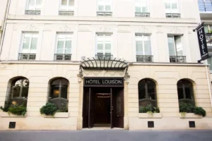 Hotel Louisonin julkisivu Pariisissa, elegantti sisäänkäynti lasikatoksella ja haussmann-arkkitehtuurilla.