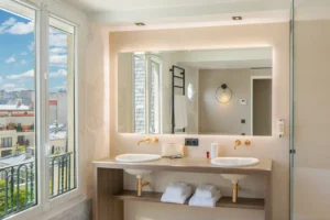Hotel Louisonin valoisa huone, jossa suuri ikkuna ja näkymä Pariisin kattojen yli.