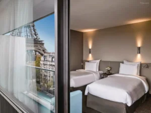 Pullman Paris Tour Eiffel -hotellin moderni huone suurella ikkunalla ja suoralla näkymällä Eiffel-torniin.